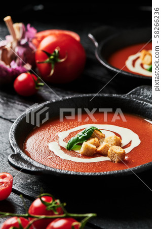 Tomato soup with cream on black wooden background. 58266236