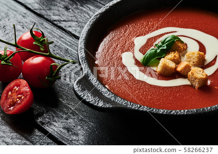 Tomato soup with cream on black wooden background. Tomato soup with cream on black wooden background. 58266237