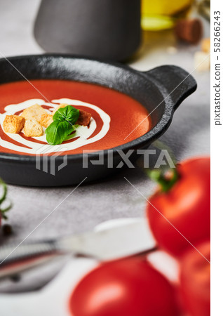 Tomato soup with cream on grey stone background. Tomato soup with cream on grey stone background. 58266243