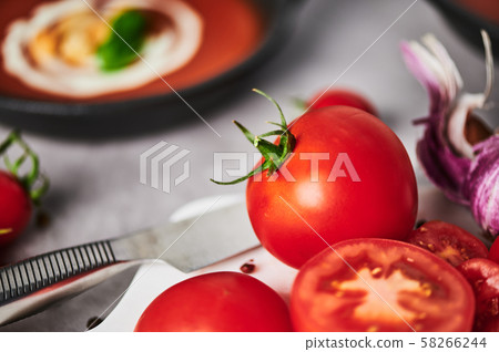 Tomatoes and tomato soup with cream on grey stone background. Tomatoes and tomato soup with cream on grey stone background. 58266244