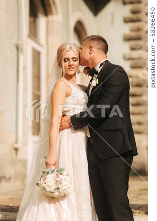 Groom and bride stand on stairs. Fashion model in elegant clothes. White long dress and stylish suit 58266450
