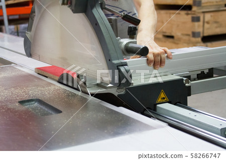 Close-up of a furniture workshop worker sawing a 58266747