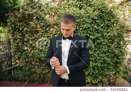 Handsome groom dressed his wedding blazer. autumn weather Handsome groom dressed his wedding blazer. autumn weather 58266862