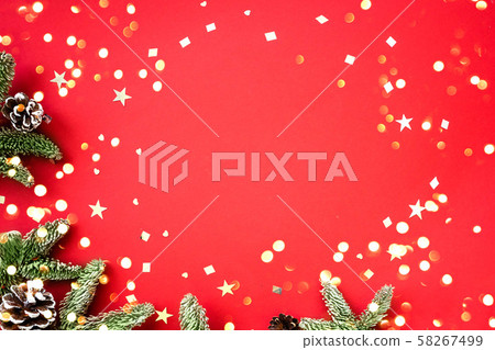 Christmas composition of fir branches and cones with shiny confetti on a red background. 58267499
