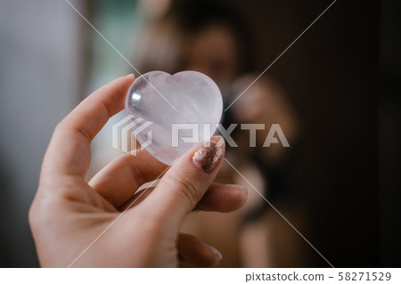 Woman holds rose quartz heart crystal 58271529