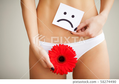 Woman holding paper with sad smile mark over her stomach. Health hygiene sexual education concept Woman holding paper with sad smile mark over her stomach. Health hygiene sexual education concept 58274490