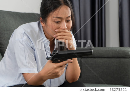 Depressed middle-aged women holding a gun in 58275221