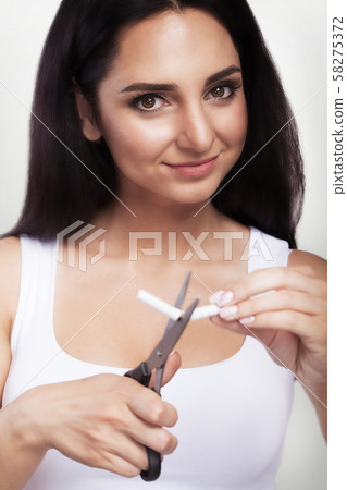 No smoking. A young girl loses a bad smoking habit. Cut the cigarette with scissors. The concept of 58275372