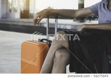 Woman with orange suitcase luggage bag, sitting in Woman with orange suitcase luggage bag, sitting in 58275845