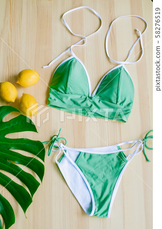 Bright trendy bikini on a wooden background with yellow lemons and tropical green leaves. Fashionable beachwear. Bright trendy bikini on a wooden background with yellow lemons and tropical green leaves. Fashionable beachwear. 58276519