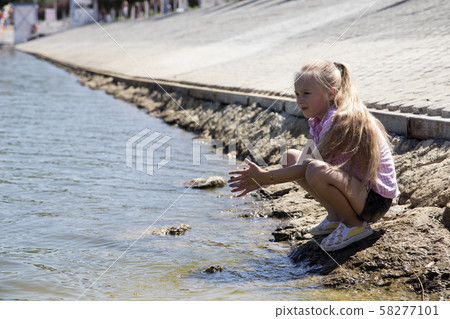 Adorable small girl sitting on the concrete dam. Adorable small girl sitting on the concrete dam. 58277101