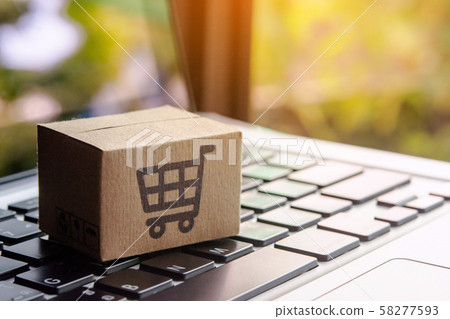 Paper cartons or parcel with a shopping cart logo on a laptop keyboard. Shopping service 58277593