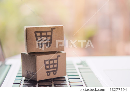 Paper cartons or parcel with a shopping cart logo on a laptop keyboard. Shopping service 58277594