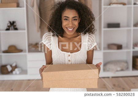 Joyful young woman demonstrating her box with clothes Joyful young woman demonstrating her box with clothes 58280028