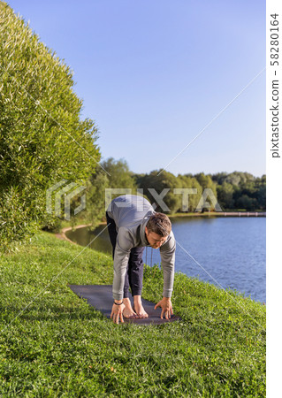 Inspired man doing yoga asanas in city park. Fitness outdoors and life balance concept. 58280164