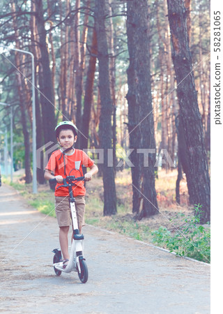 The child is engaged in riding a white scooter. 58281065