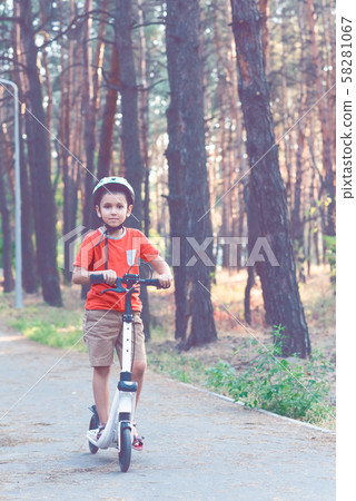 The child is engaged in riding a white scooter. 58281067