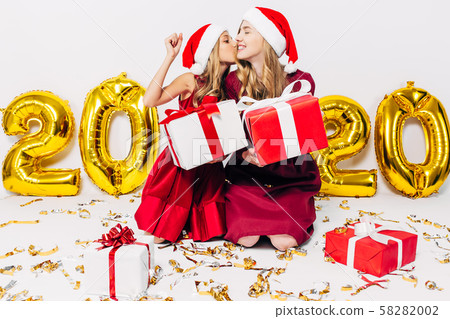 Cheerful mom and her cute daughter in Santa hats, 58282002