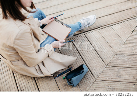 A young girl sketching near a lake in the autumn forest. 58282253