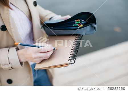 A young girl sketching near a lake in the autumn forest. 58282268