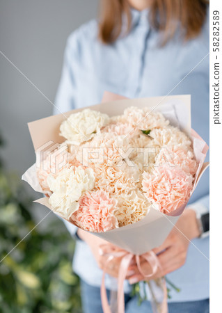 Mono bouquet. Bunch of carnation flowers pastel color. Spring bunch in woman hand. Present for Mono bouquet. Bunch of carnation flowers pastel color. Spring bunch in woman hand. Present for 58282589