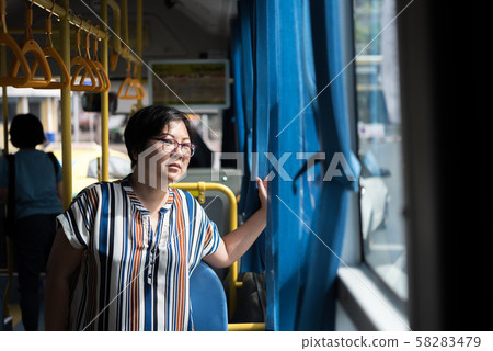 Asian woman travel by passenger bus in city 58283479