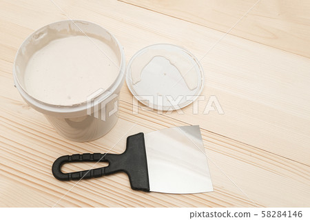 Spatula and a bucket of white putty on wooden Spatula and a bucket of white putty on wooden 58284146