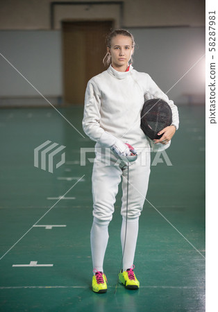 A young woman fencer standing in the gym 58287981