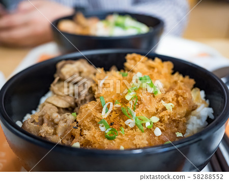 Katsudon is a popular Japanese food, a bowl of rice topped with a deep-fried pork cutlet, egg, vegetables, and condiments. Katsudon is a popular Japanese food, a bowl of rice topped with a deep-fried pork cutlet, egg, vegetables, and condiments. 58288552