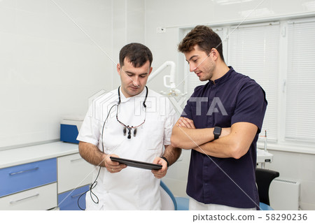 Two hospital workers examinig resoults of patient's analyses together Two hospital workers examinig resoults of patient's analyses together 58290236