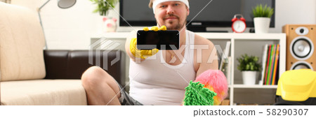 A young smiling man holds a smartphone 58290307