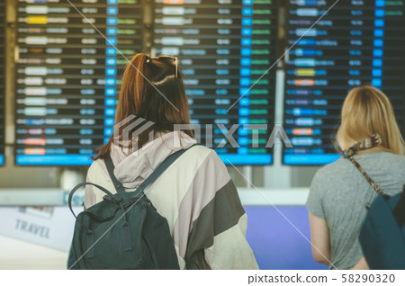 Passengers looking at the flight information board and checking their flight in international airport 58290320