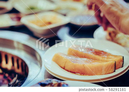 People grilling meat on a smokeless barbecue grill in a restaurant. 58291181