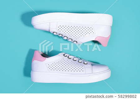 White sneakers on light turquoise background 58299802