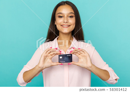 Glad and happy female person holding credit card standing on the blue background. Glad and happy female person holding credit card standing on the blue background. 58301412