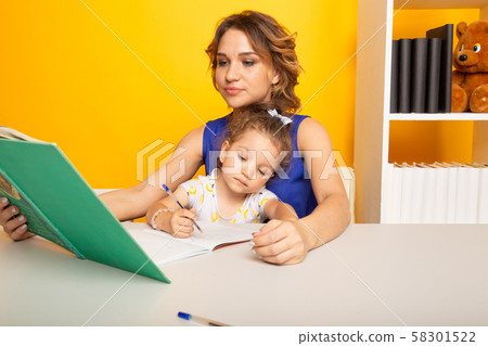 Mom with little baby girl together at home sitting at the table. 58301522