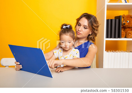 Mother and kid spending time together by sitting and learning. 58301530