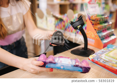 Young caucasian female woman cashier in toy store. Woman use cashier counter in kids mall Young caucasian female woman cashier in toy store. Woman use cashier counter in kids mall 58301819