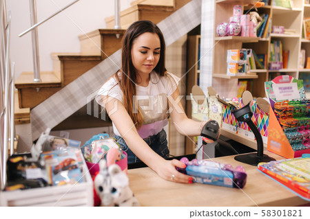 Young caucasian female woman cashier in toy store. Woman use cashier counter in kids mall Young caucasian female woman cashier in toy store. Woman use cashier counter in kids mall 58301821