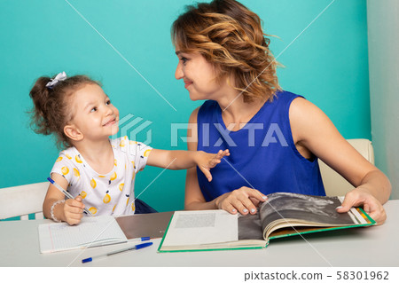 Pretty family concept. Mom and daughter sitting together and studying at home. 58301962