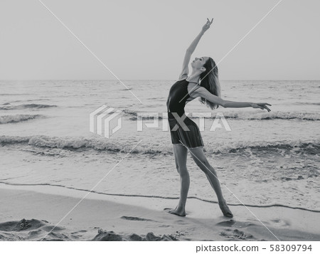 Flexible ballerina in dress dancing ballet on sea sandy beach in morning light Flexible ballerina in dress dancing ballet on sea sandy beach in morning light 58309794