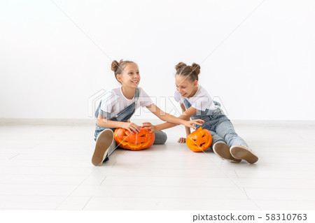 Happy Halloween, holidays and childhood concept - Cute little twins sisters girls with a pumpkins Happy Halloween, holidays and childhood concept - Cute little twins sisters girls with a pumpkins 58310763