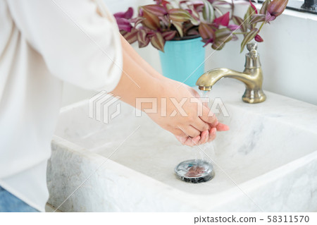 The woman hand is going to open the faucet to wash 58311570