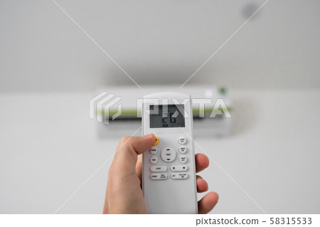 Man's hand using remote controler. Hand holding rc and adjusting temperature of air conditioner 58315533