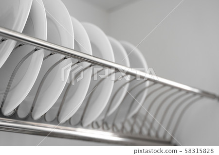 Dish drying metal rack with big nice white clean plates. Traditional comfortable kitchen. Open white Dish drying metal rack with big nice white clean plates. Traditional comfortable kitchen. Open white 58315828