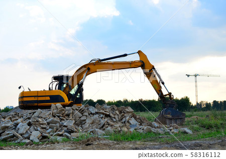 Excavator with crusher bucket for crushing concrete. Construction waste recycling Excavator with crusher bucket for crushing concrete. Construction waste recycling 58316112