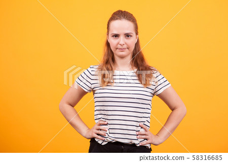 Pretty girl holding hands on hips in studio over yellow background Pretty girl holding hands on hips in studio over yellow background 58316685