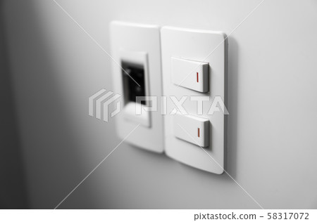 White switch on a white wall with two switches and one common switch. 58317072