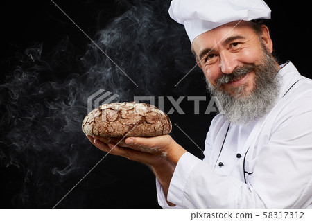 Smiling Baker Holding Fresh Bread against Black Smiling Baker Holding Fresh Bread against Black 58317312