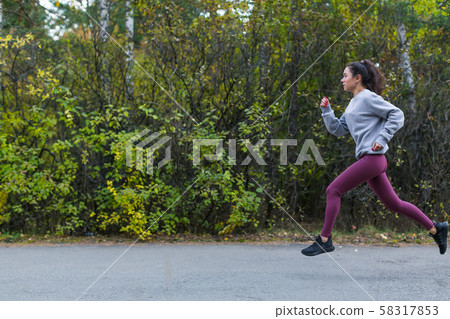 Side view of a running woman in autumn city park 58317853